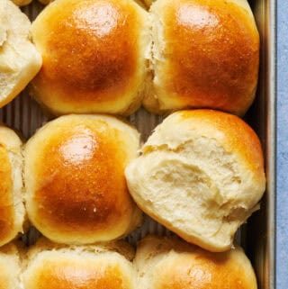 overhead view of a tray of fresh sourdough discard dinner rolls with one turned on its side