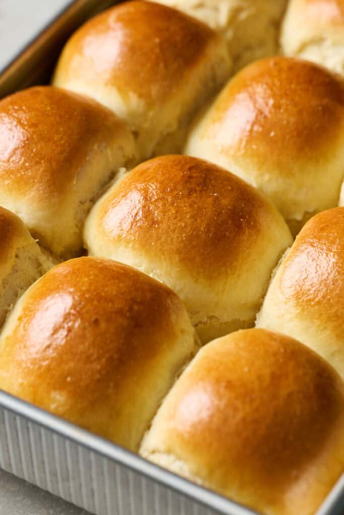 side view of a pan of golden brown sourdough discard dinner rolls