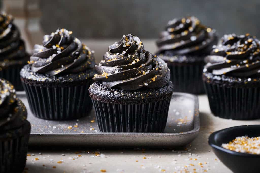 black velvet cupcakes on a silver plate surrounded by sprinkles