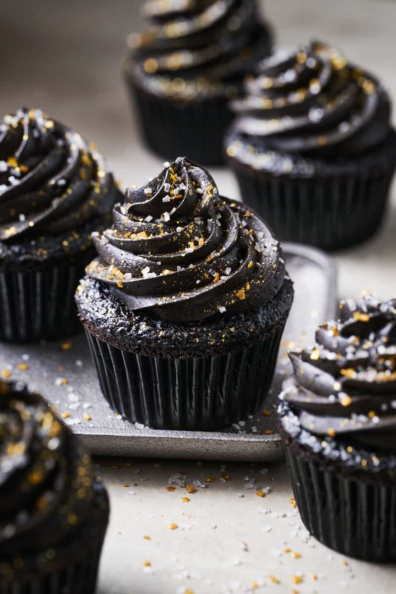 black velvet cupcake with black chocolate frosting topped with edible glitter and sprinkles