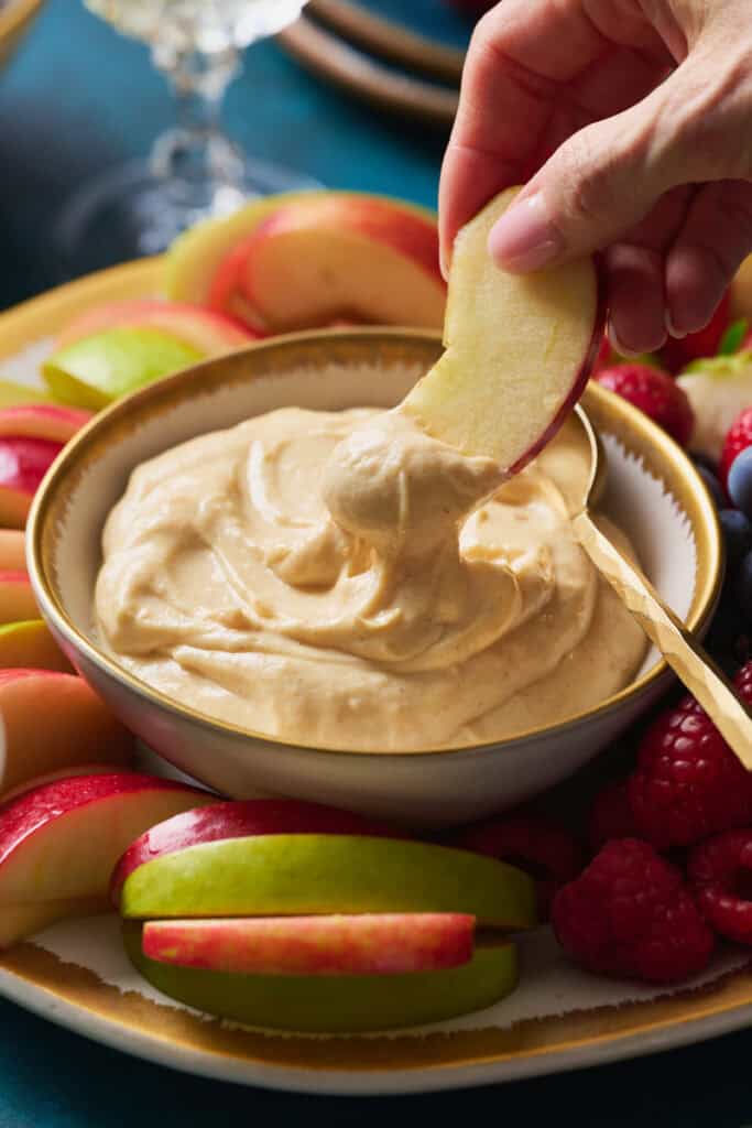 dipping an apple into cheesecake fruit dip