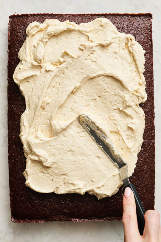 spreading frosting on the gingerbread cake with an offset spatula