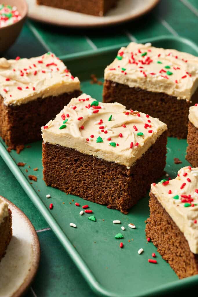 Slices of gingerbread cake with cinnamon molasses ermine frosting on a green sheet pan