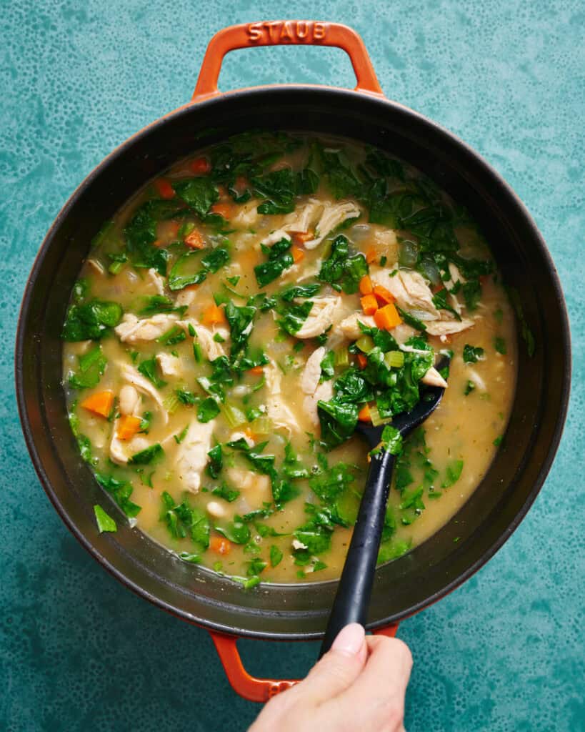 stirring soup with greens, turkey, parmesan and lemon added to the whole soup