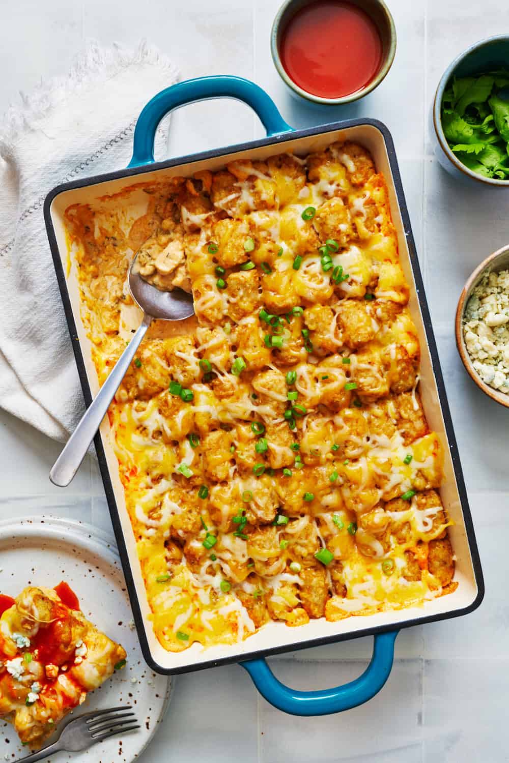 overhead view of buffalo chicken tater tot casserole in a 9 x 13 inch dish with a serving removed