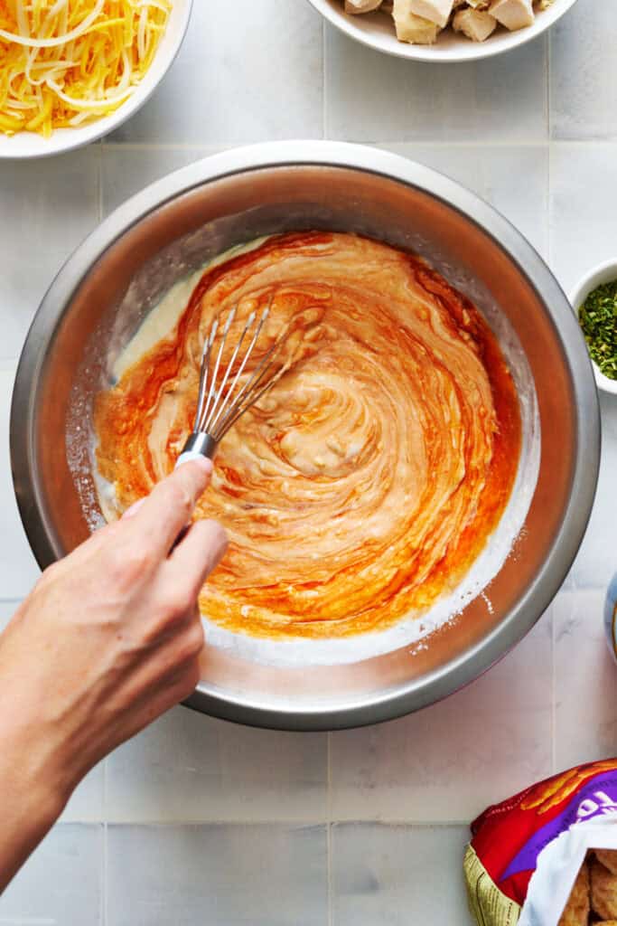 stirring sauce components together for buffalo chicken tater tot casserole