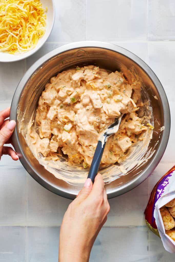 folding in cheese, chicken and diced celery into the sauce for buffalo chicken tater tot casserole