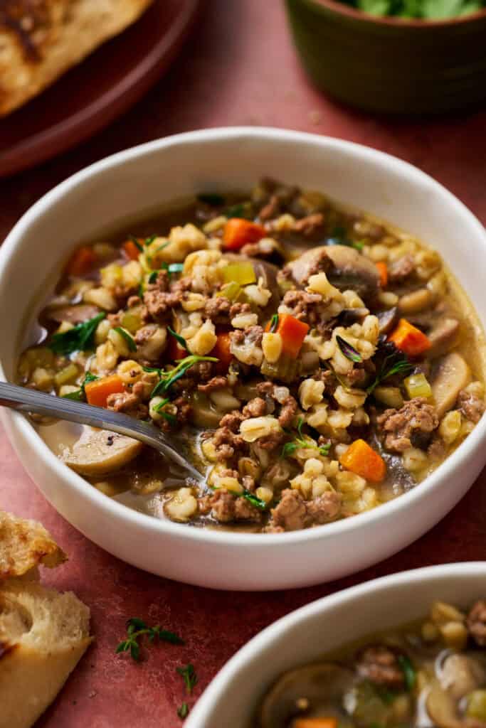 Ground Beef Barley soup made in a pressure cooker in a bowl with crusty bread on the side