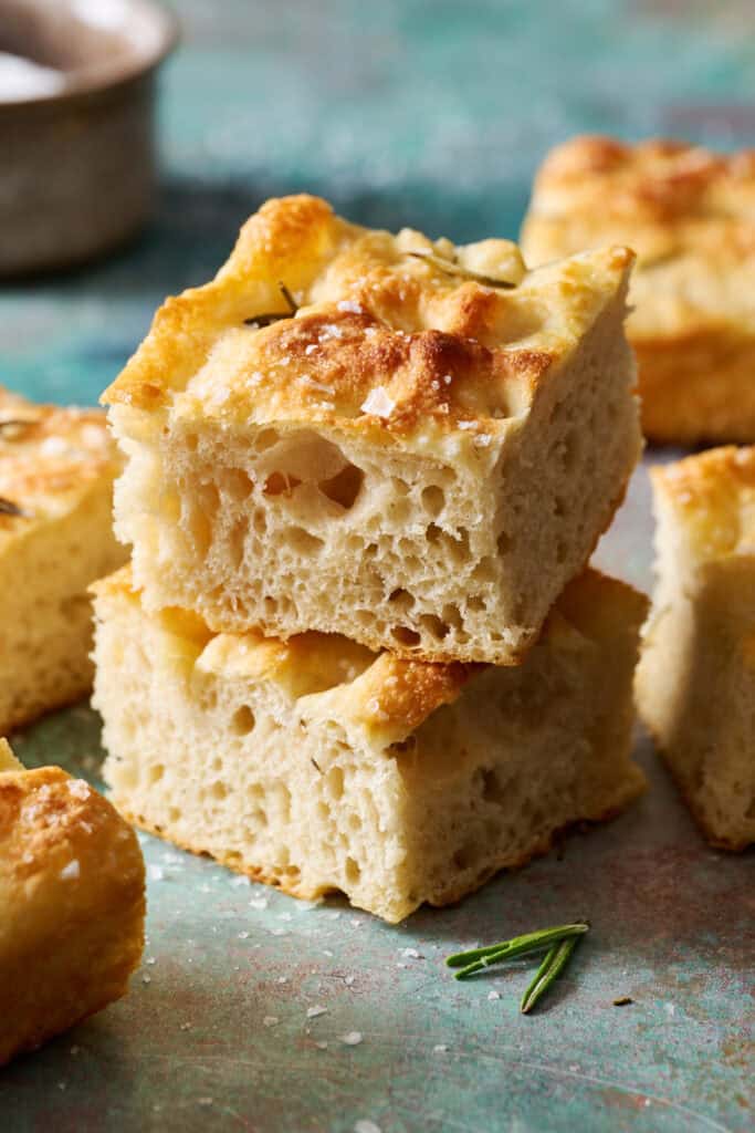 two slices of sourdough discard focaccia stacked on eachother with other slices around