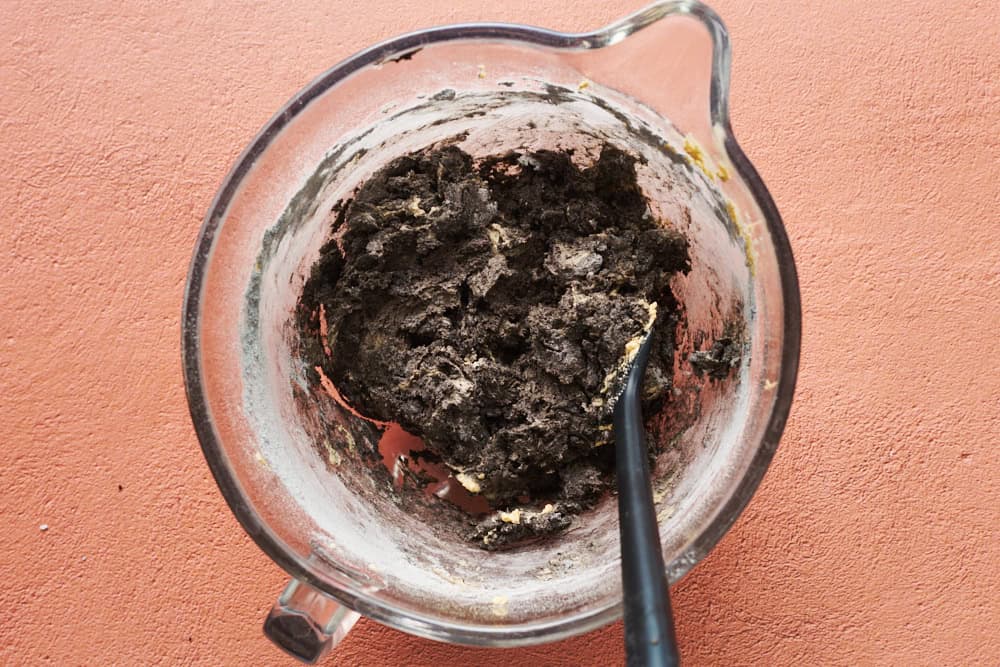 the dry ingredients added to the wet ingredients in a glass bowl with a spatula