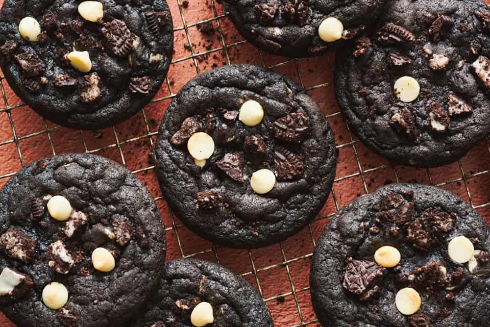 Chocolate Cookies and Cream Cookies on a cooling rack with crumbs sprinkled around.