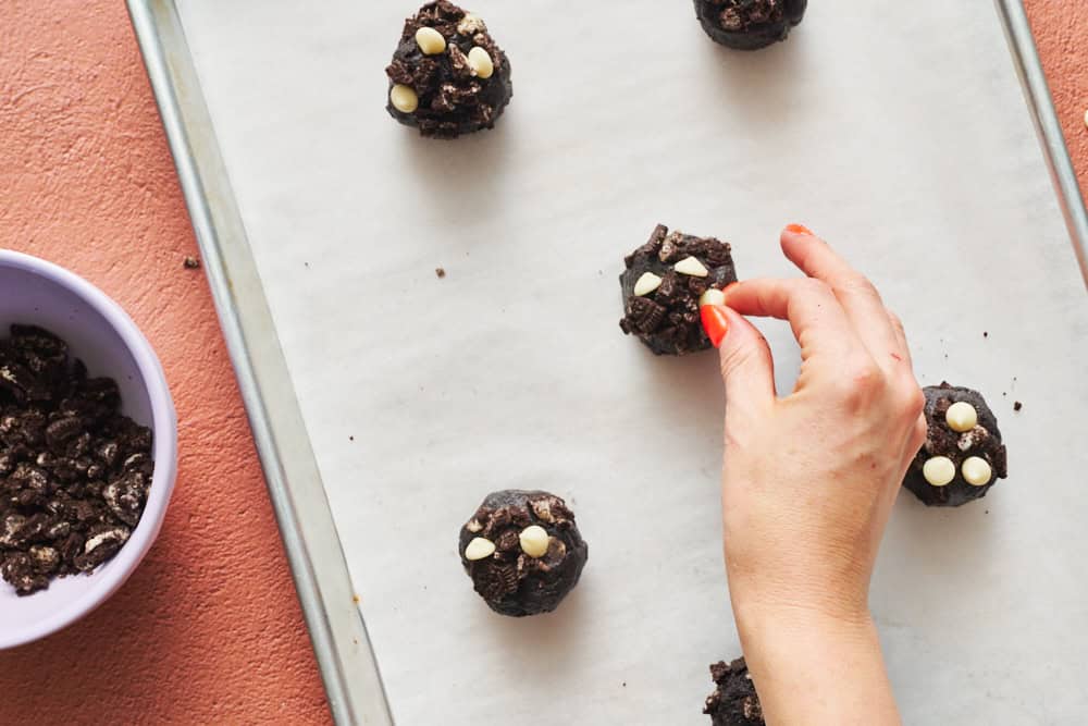 adding white chocolate chips to cookie dough balls