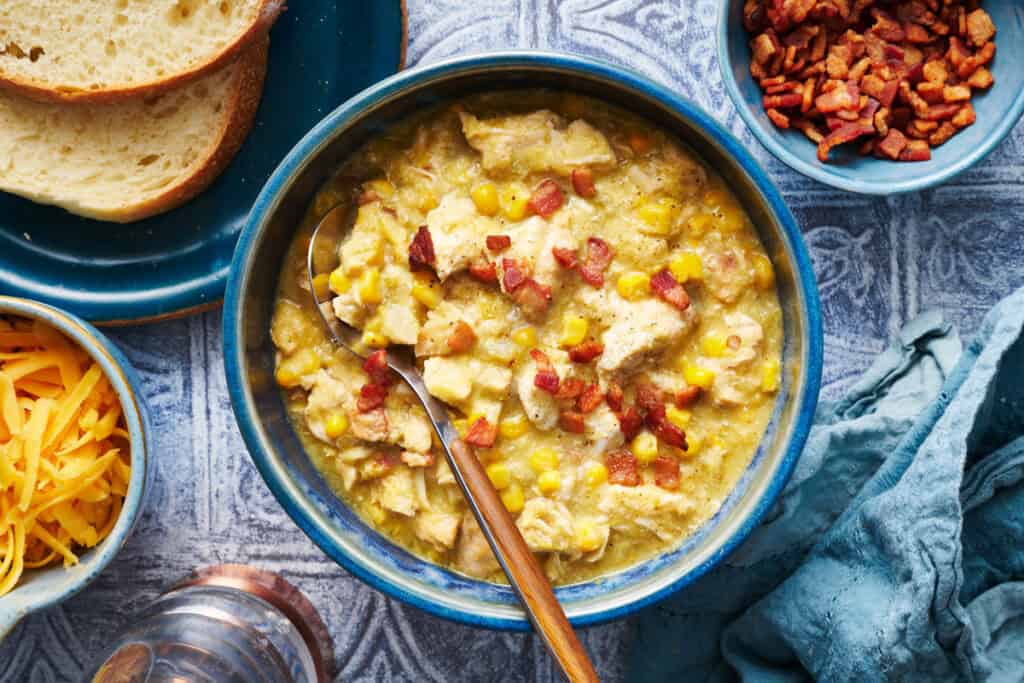 a bowl of chicken corn chowder with bacon bits on top