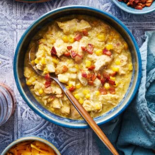 a bowl of chicken corn chowder with bacon bits on top