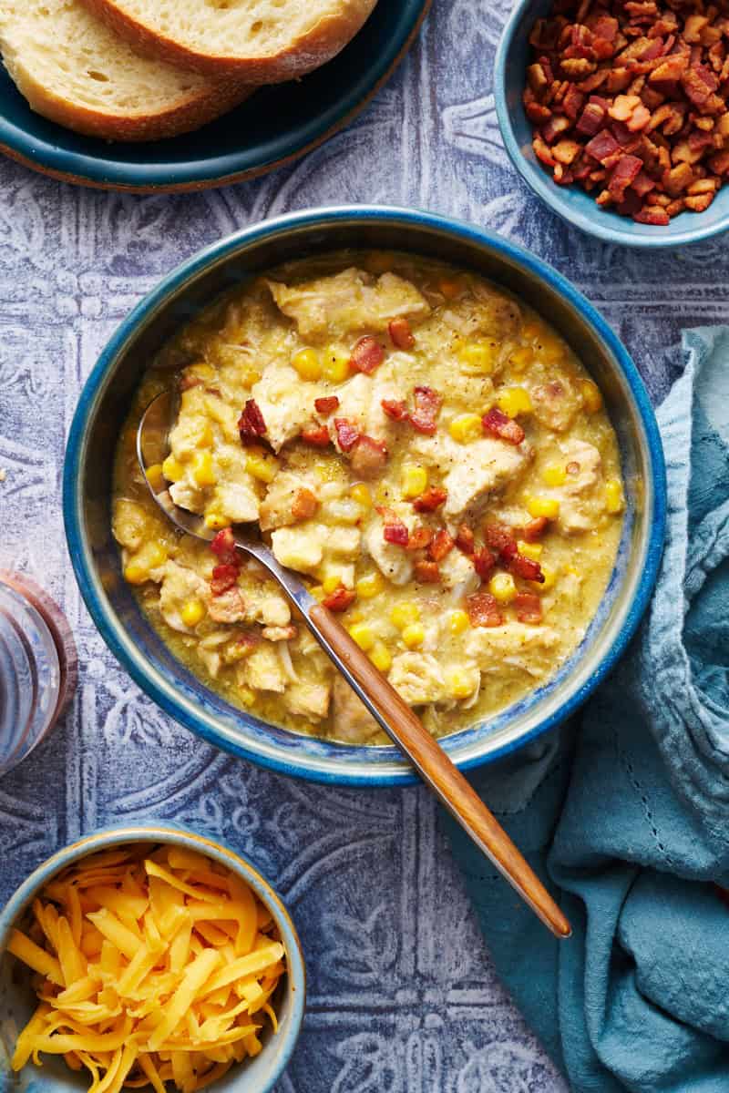 bowl of chicken corn chowder with a spoon and topped with crispy bacon bits