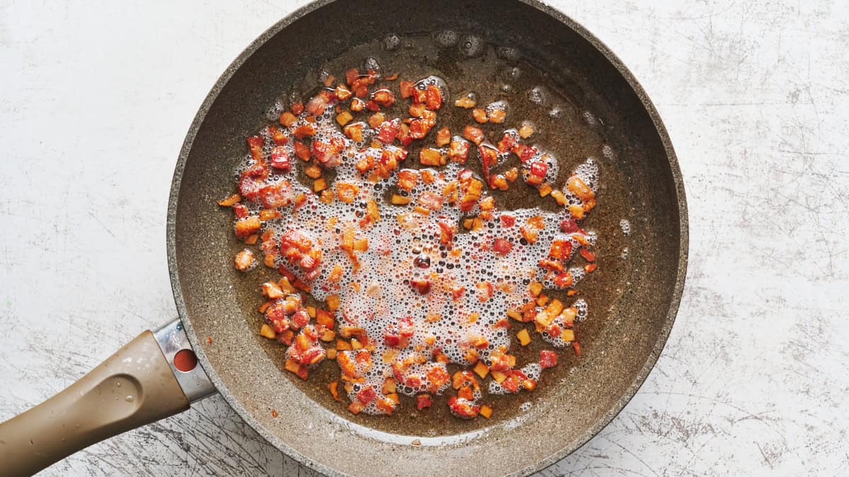 bacon bits being cooked in a saute pan