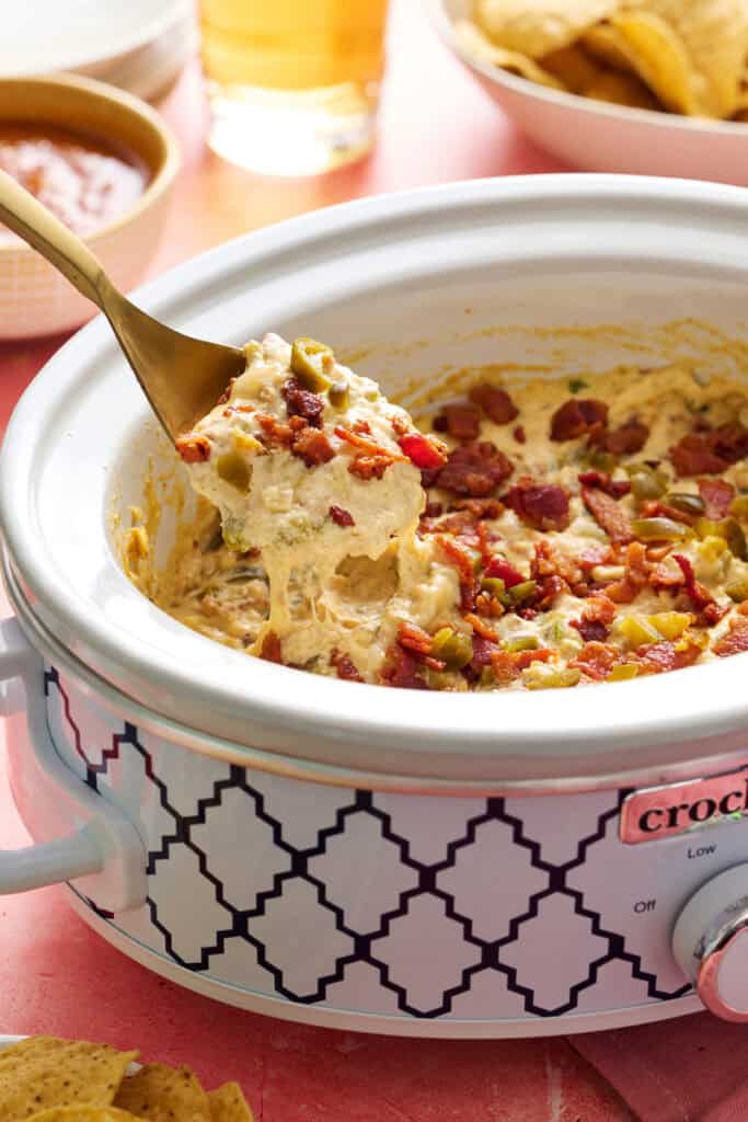 scooping out jalapeno popper dip from a crock pot