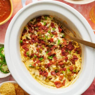 overhead view of a slow cooker with jalapeno popper dip ready to serve with chips and salsa on the side