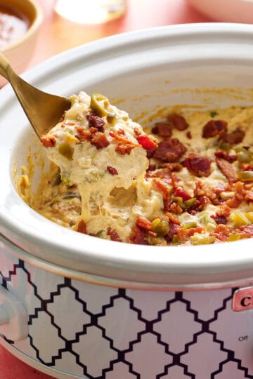 overhead view of a slow cooker with jalapeno popper dip ready to serve with chips and salsa on the side