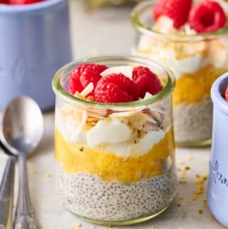 a glass jar with pineapple chia seed pudding topped with coconut and raspberries