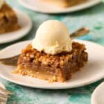 Bourbon pecan pie bar on a plate topped with ice cream and a fork on the side.