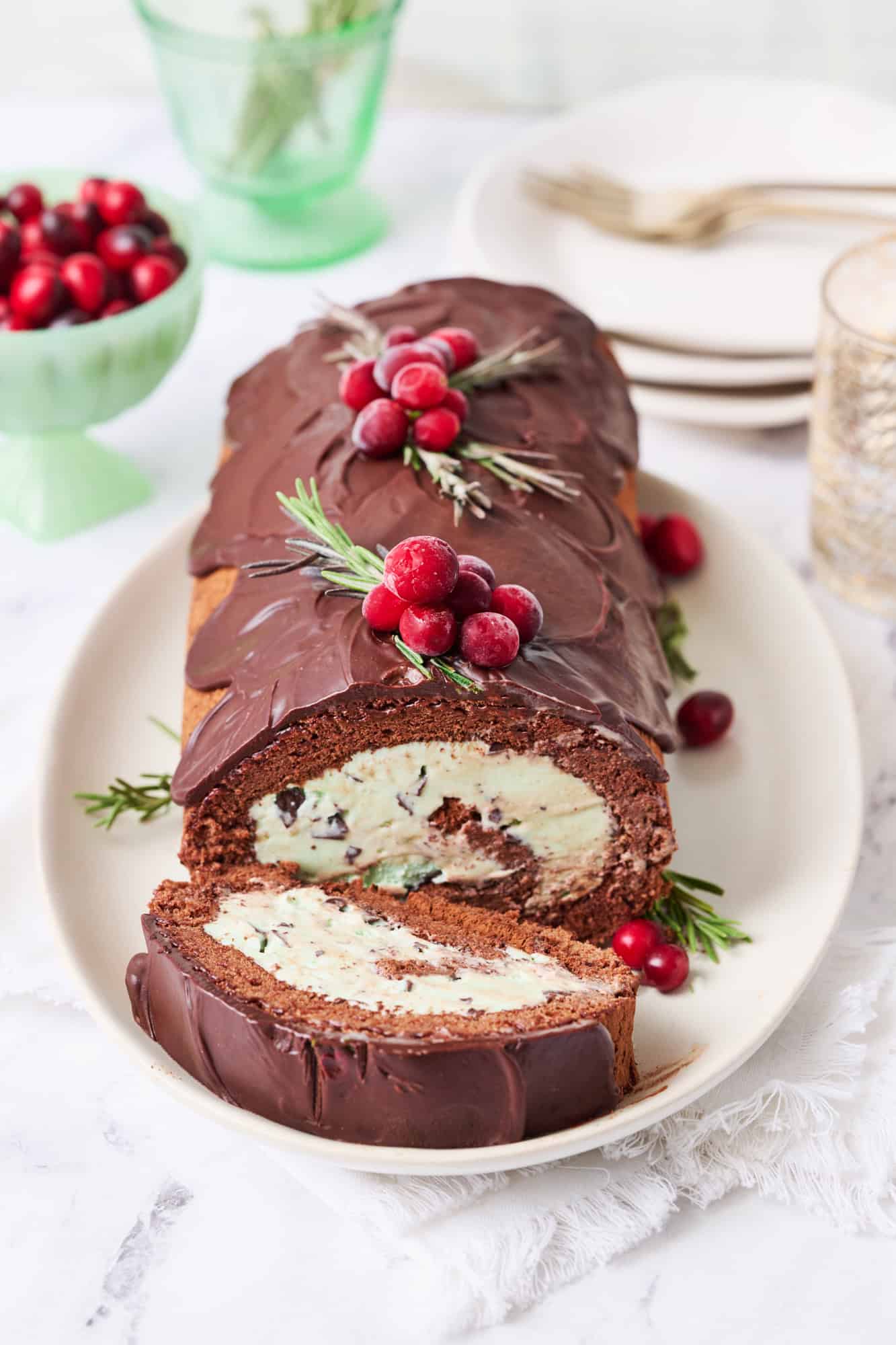 an ice cream roll cake with chocolate ganache frosting and mint ice cream on a platter