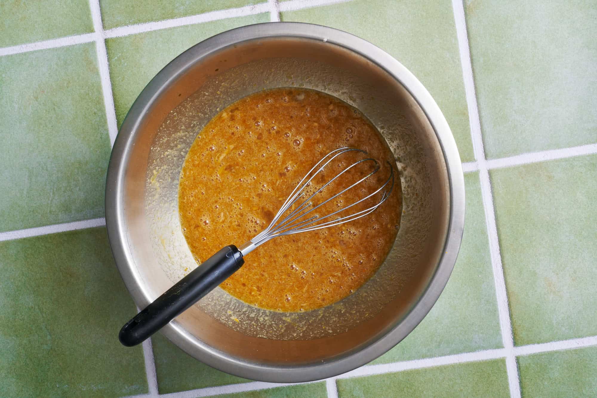 liquid ingredients for carrot cake cupcakes in a metal bowl with a whisk