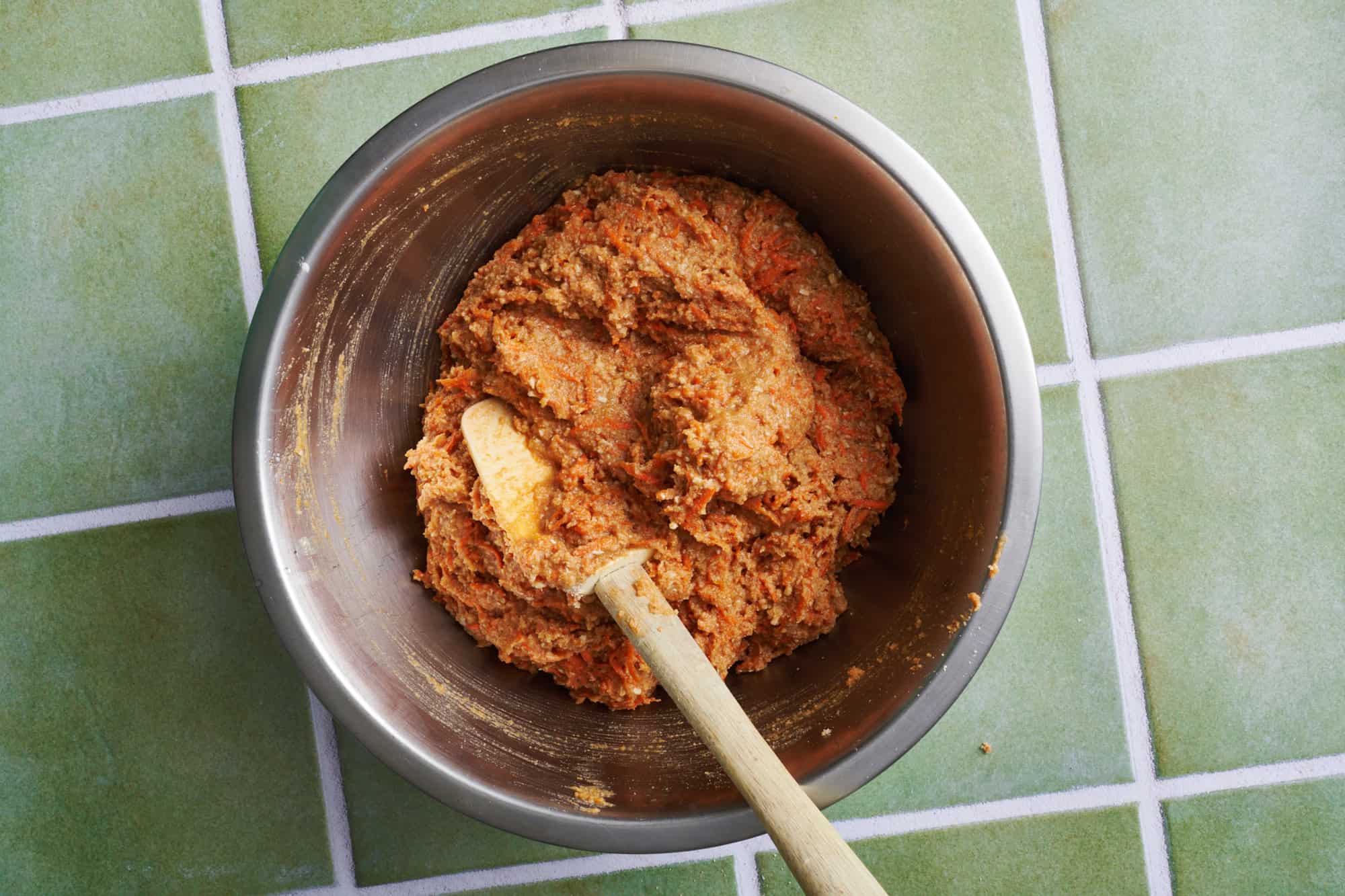 batter for healthy carrot cake cupcakes in a metal bowl with a spatula