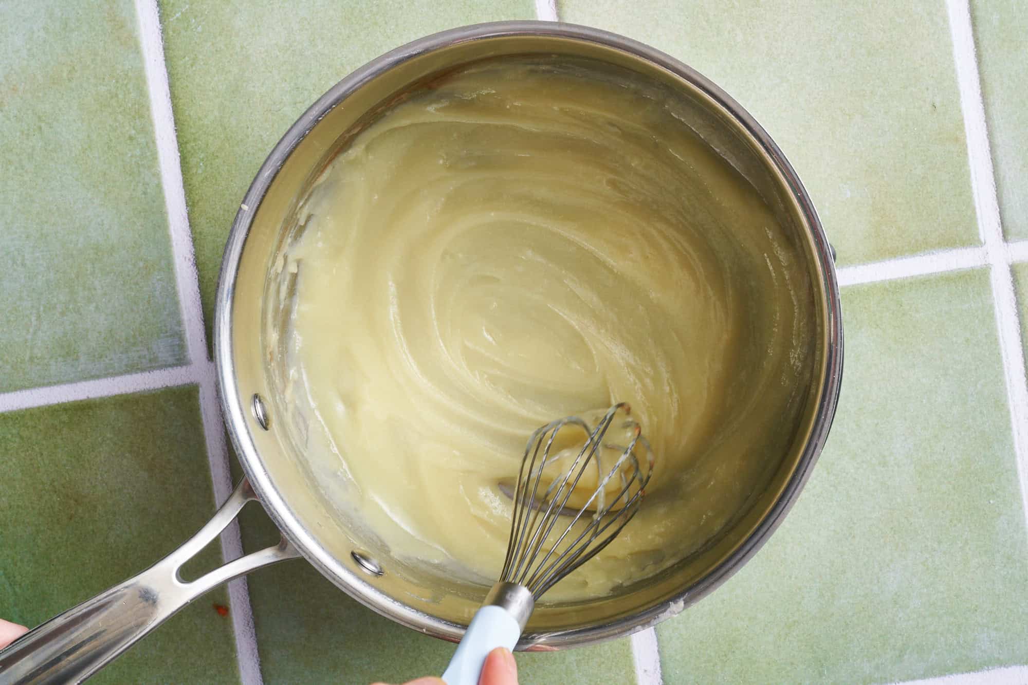 whisking the frosting base in a metal put