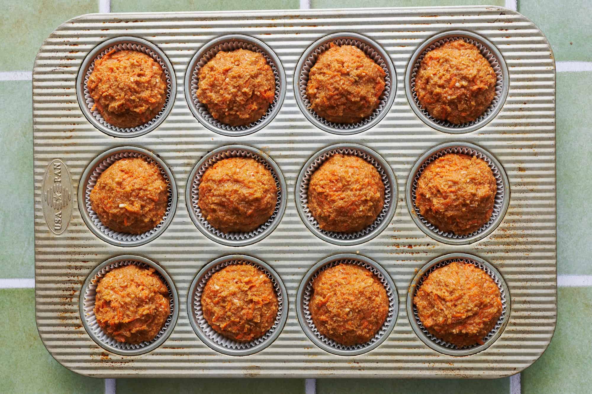 healthy carrot cake cupcake batter in a cupcake pan with cupcake liners