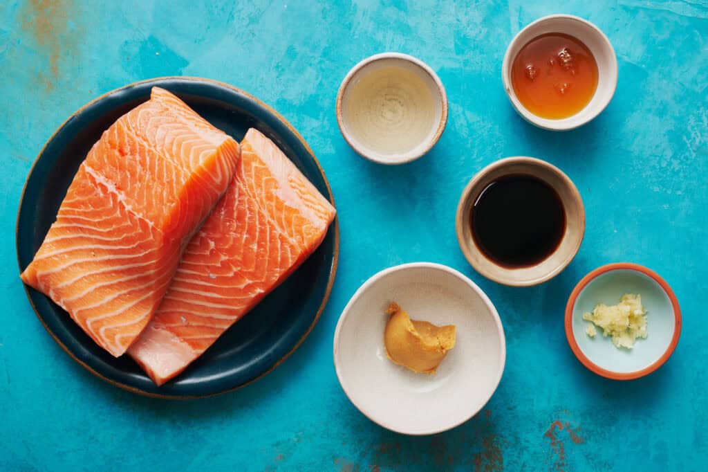 overhead view of the ingredients to make miso salmon bowls including garlic, rice wine, soy sauce, honey, and miso paste