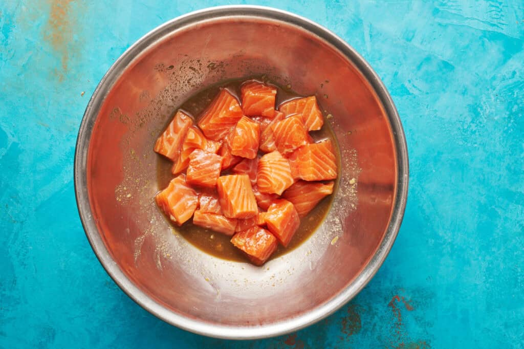 overhead of a bowl with marinade and salmon pieces