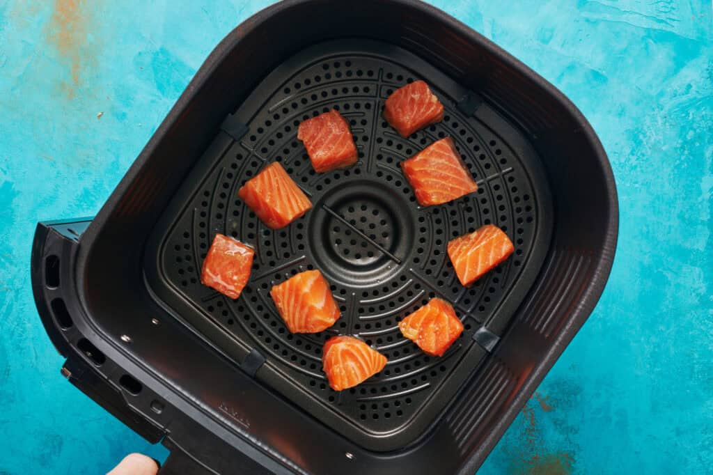 salmon bites placed inside the air fryer basket