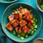 Overhead of miso glazed salmon bites over a bed of quinoa and cucumers.