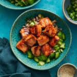 Overhead of miso glazed salmon bites over a bed of quinoa and cucumers.