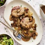 Overhead view of a platter with Oven Hamburger Steaks smothered in mushroom gravy with onions and mushrooms scattered around.