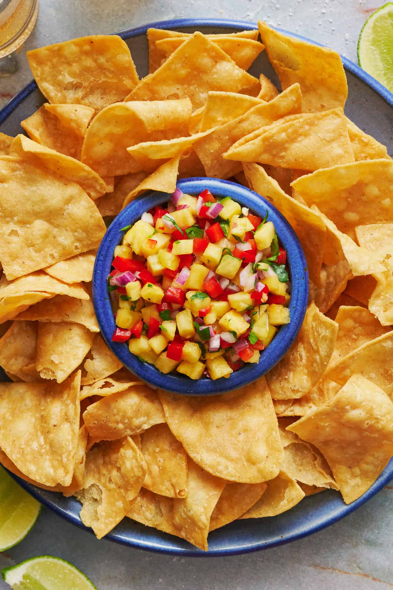 overhead view of a blue bowl filled with pineapple pico de gallo with chips