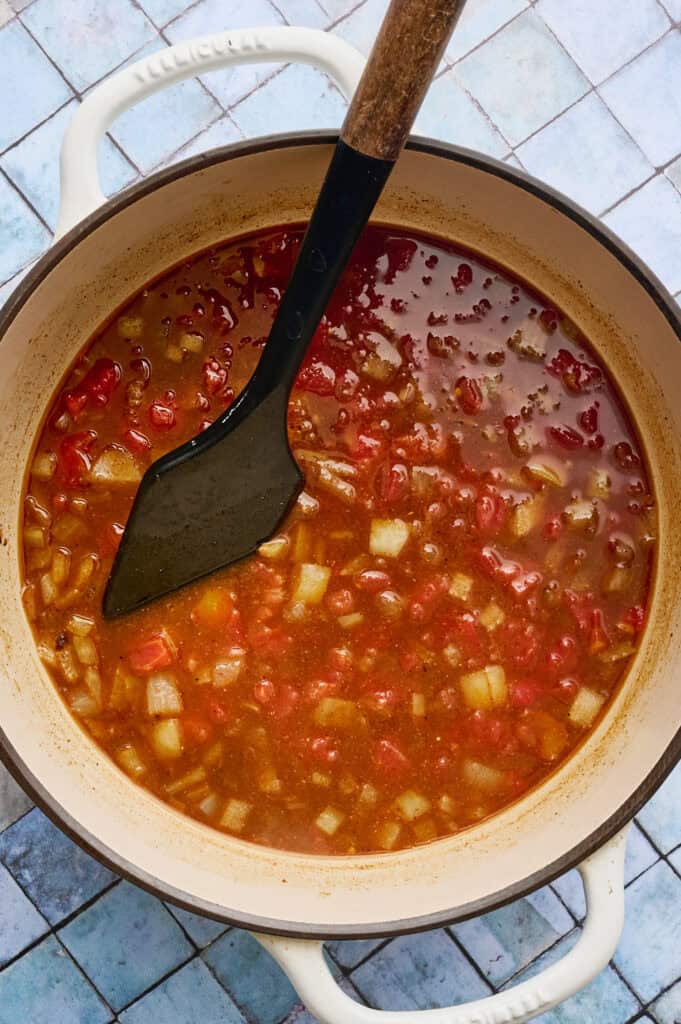 a large pot with tomatoes and broth added