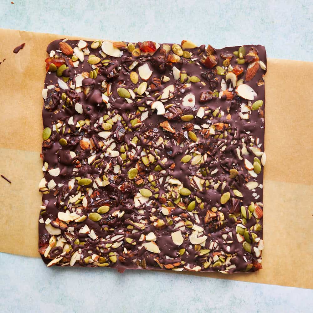 overhead view of chocolate bark with sea salt, almonds, pumpkin seeds and dates after being removed from the pan before being chopped