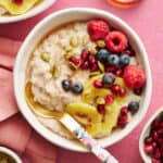 fonio porridge in a bowl topped with kiwi, raspberries, blueberries, pumpkin seeds and pomegranate