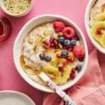 fonio porridge in a bowl topped with kiwi, raspberries, blueberries, pumpkin seeds and pomegranate