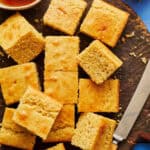 sliced sourdough discard cornbread on a cutting board with honey and a knife