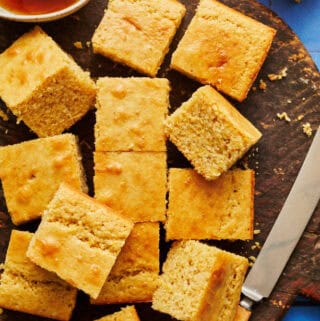 sliced sourdough discard cornbread on a cutting board with honey and a knife