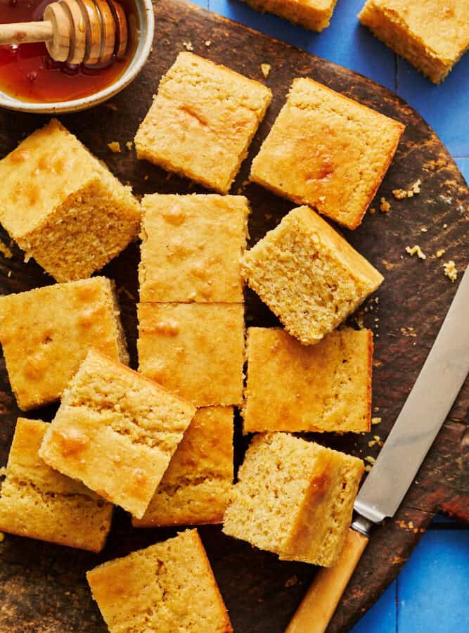 sliced sourdough discard cornbread on a cutting board with honey and a knife