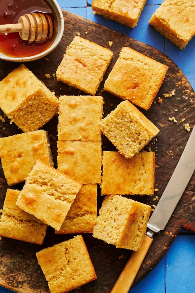 sliced sourdough discard cornbread on a cutting board with honey and a knife