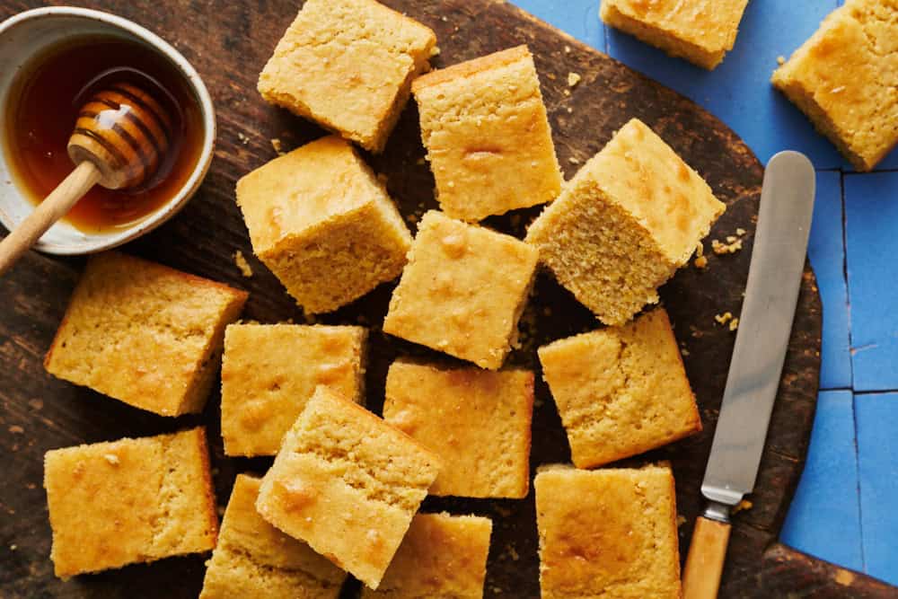 sliced sourdough discard cornbread on a cutting board with honey and a knife