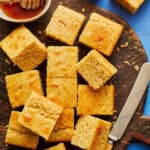 sliced sourdough discard cornbread on a cutting board with honey and a knife