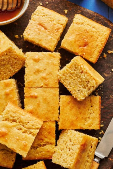 sliced sourdough discard cornbread on a cutting board with honey and a knife