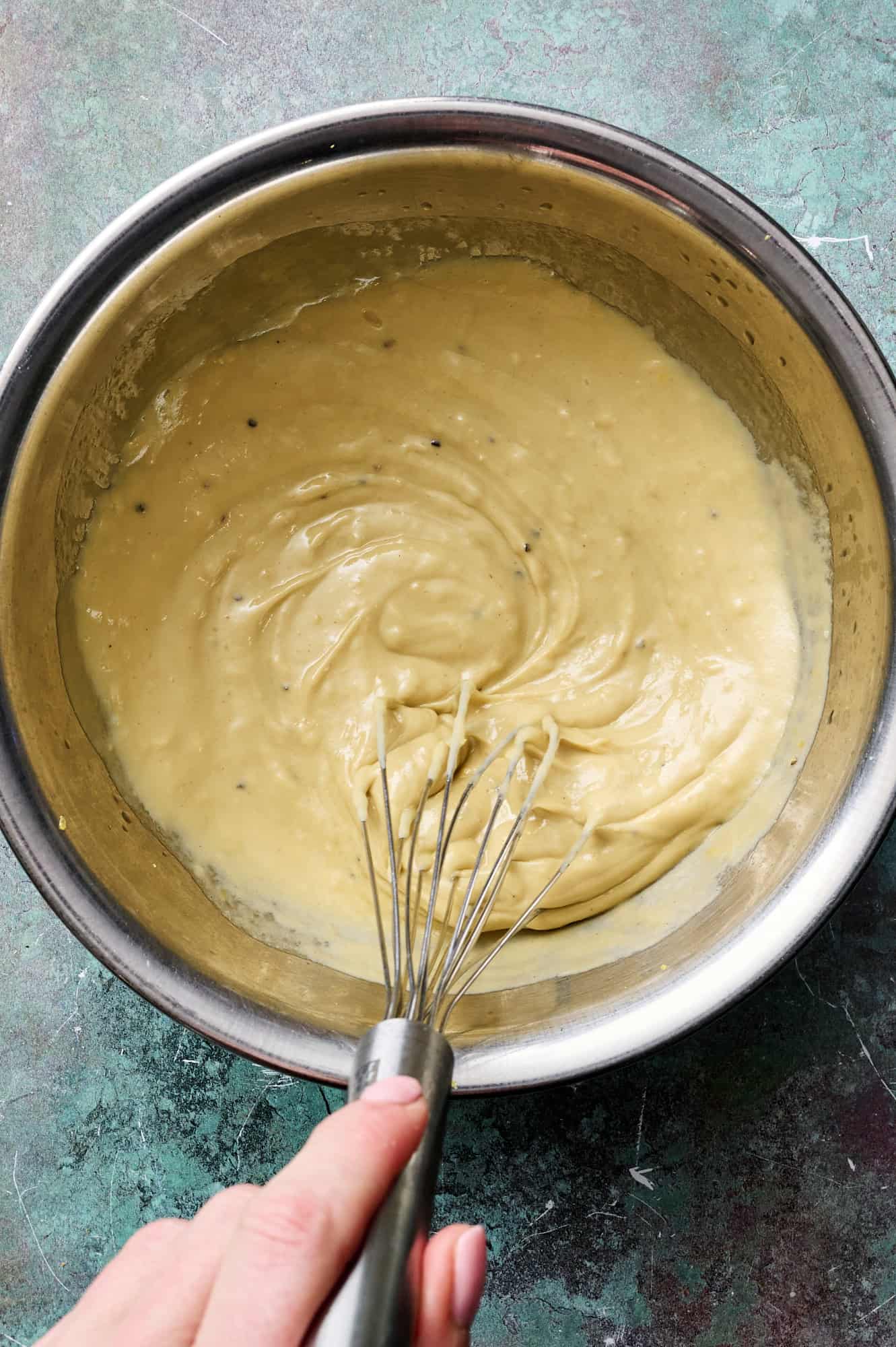 whisking the lemon tahini dressing in a large bowl