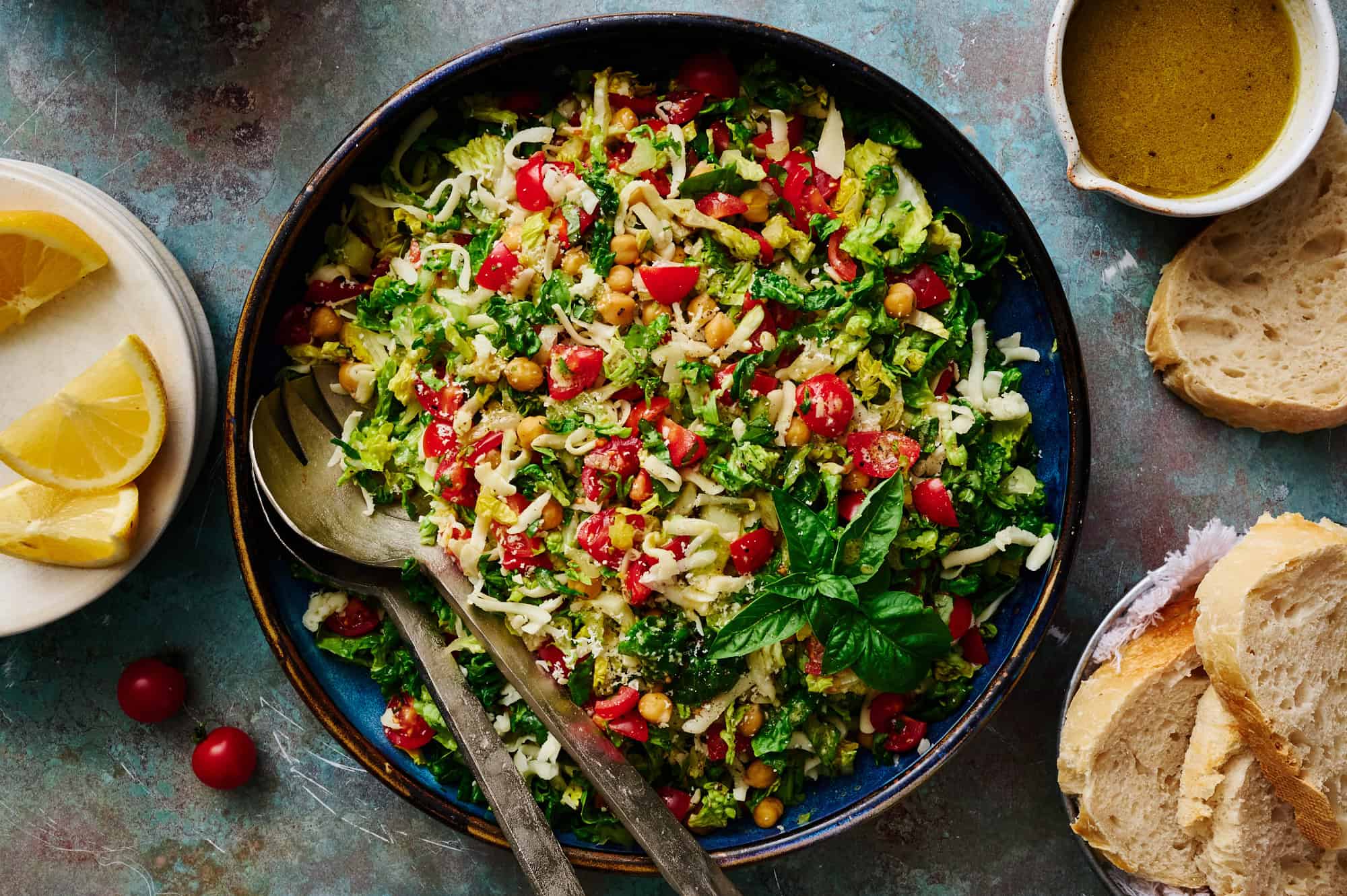 a large serving bowl filled with salad with creamy mozzarella, fresh tomatoes, basil and romaine lettuce